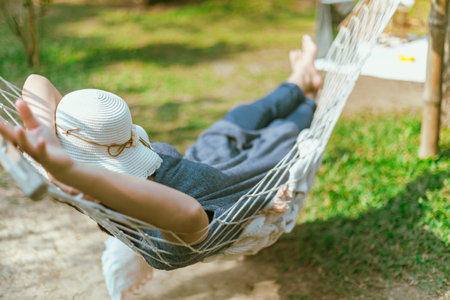 Women covering face with hat sleeping on hammock at the gardenの写真素材