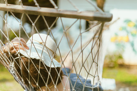 Women covering face with hat sleeping on hammock at the gardenの写真素材