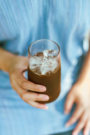 Close up of Hand holding a glass of Iced Americano or back coffeeの写真素材
