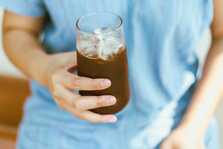 Close up of Hand holding a glass of Iced Americano or back coffeeの写真素材