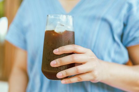 Close up of Hand holding a glass of Iced Americano or back coffeeの写真素材