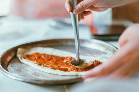 Spreading tomato sauce on pizza pan, selective focusの写真素材