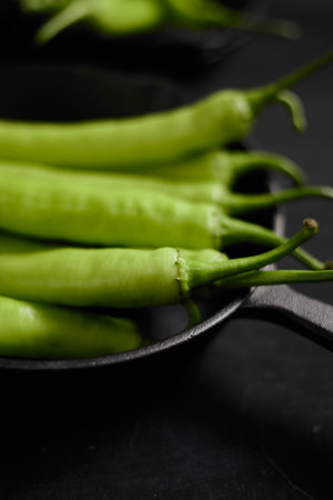 Fresh green chilli on a black background.の写真素材