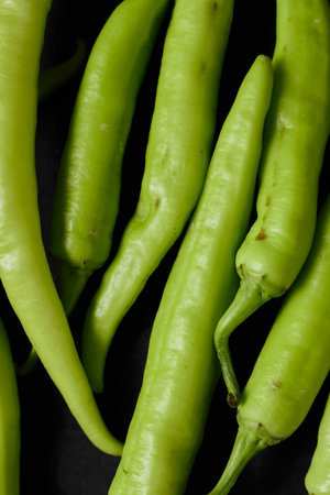 Fresh green chilli on a black background.の写真素材
