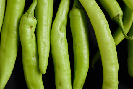 Fresh green chilli on a black background.の写真素材