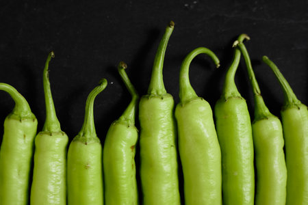 Fresh green chilli on a black background.の写真素材
