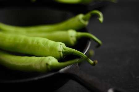 Fresh green chilli on a black background.の写真素材