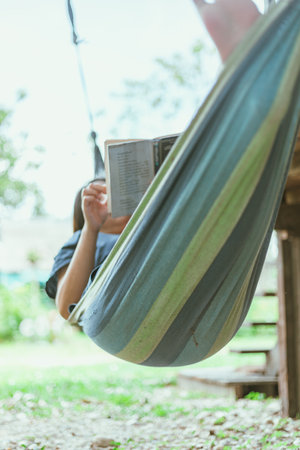 Happy young woman relaxing in a hammock in the gardenの写真素材