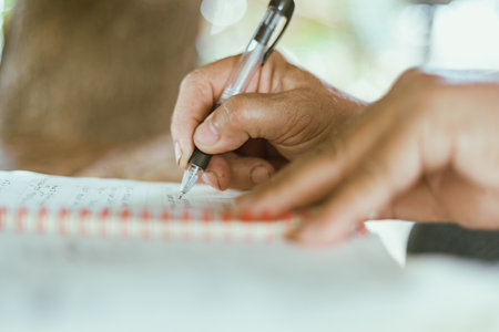 A hand writing on a notebook on a table, selective focusの写真素材