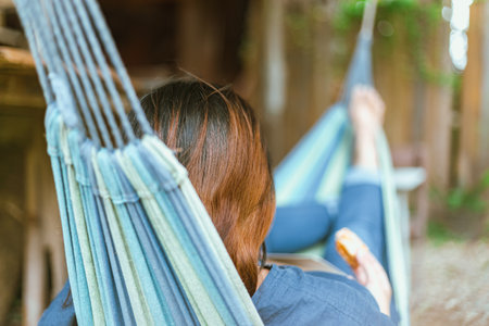 Happy young woman relaxing in a hammock in the gardenの写真素材