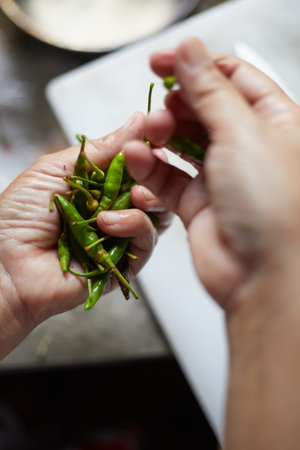 Close up hand holding fresh green chili peppers