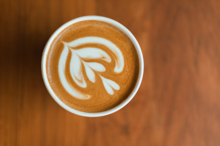 Close up cup of hot latte art coffee on wooden table ,focus at white foamの写真素材