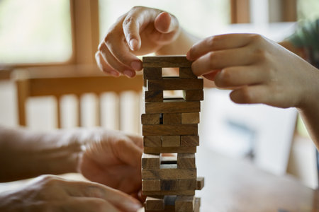 Closeup hand holding and playing Jenga or Tumble tower wooden block gameの写真素材