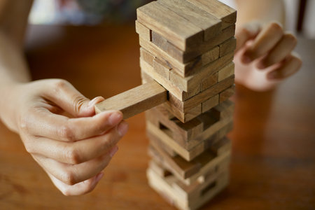 Closeup hand holding and playing Jenga or Tumble tower wooden block gameの写真素材