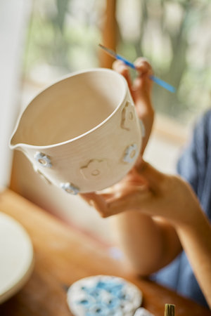 Close up hand of woman painting her pottery ceramic at studio.Â 