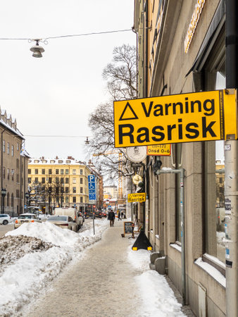 Stockholm, Sweden - February 4 2021: Yellow warning sign with translation Warning for falling snow or iceの写真素材