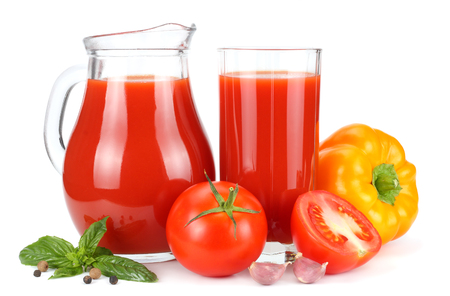 Tomato juice in glass jug with tomato, garlic, spices, and basil isolated on white backgroundの写真素材