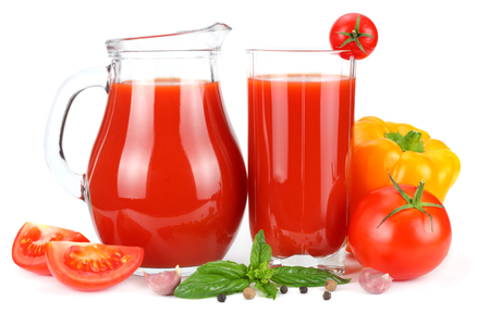Tomato juice in glass jug with tomato, garlic, spices, and basil isolated on white backgroundの写真素材