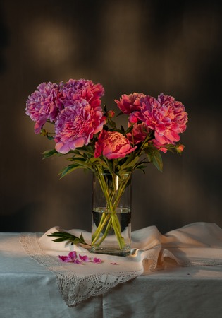 beautiful bouquet of pink peonies on a table in a glass vase.の写真素材