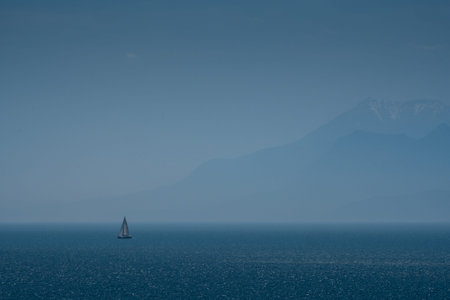 sailboat in the sea, mountains in the background