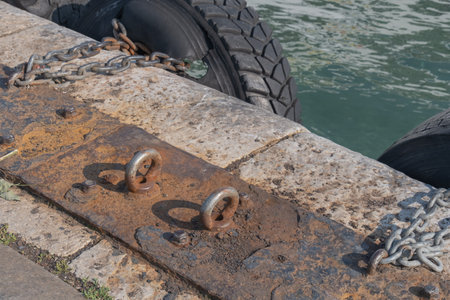 worn and dirty concrete floor. old truck tires at the pier, tire bumpers. rusty metal rings, chains