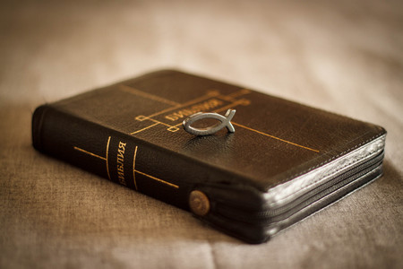 picture of a book Bible close-up in black leather binding with a zipper with a Christian pendant symbol fish on a gray background.の写真素材