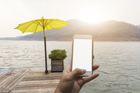 Hand holding smart phone on riverの写真素材