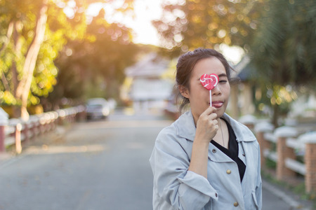 Young woman Tongue with candy on blurred bokeh backgroundの写真素材
