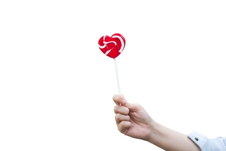 hand holding red heart lollipop on white isolated backgroundの写真素材