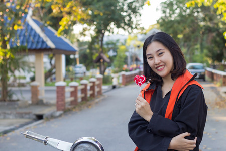Asian young woman holding red heart lollipopの写真素材