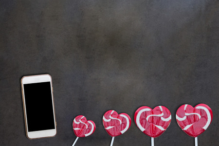 Smart phone and lollipop on table backgroundの写真素材