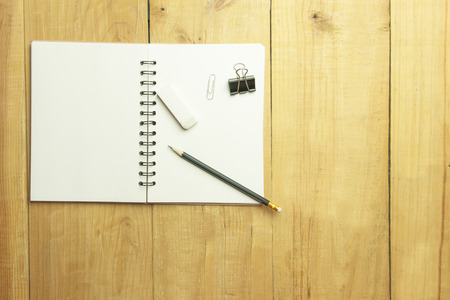 Top view  of pencil and binder clip and eraser over blank book on wooden table. spaceの写真素材