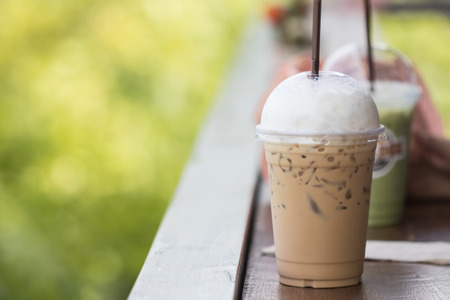 Close up ice cappuccino on wooden table with green nature backgroundの写真素材