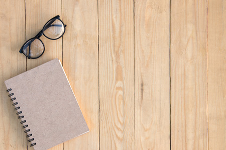 Book and eyeglasses on brown wooden table. copy spaceの写真素材