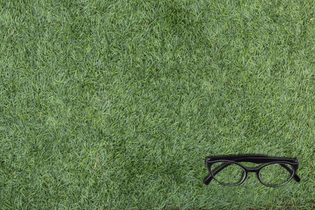 Eyeglasses on green artificial grass copy space, top view background