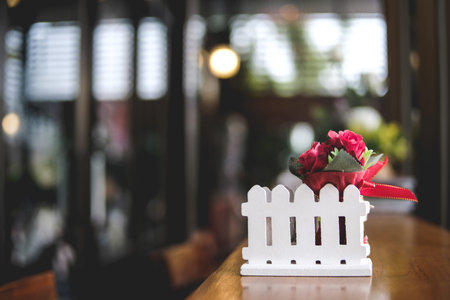 Copy space image artificial small red rose bouquet on wooden table of brown in blurred coffee cafe...