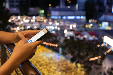 Woman hold mobile phone and checking business online in city, mock up on screenの写真素材