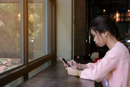 Woman using smart phone on wooden table, people and technology conceptの写真素材