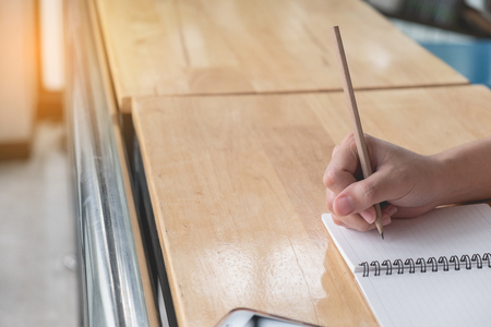Close up. Woman hand is writting on notepad with pencil beside windown, Working business conceptの写真素材