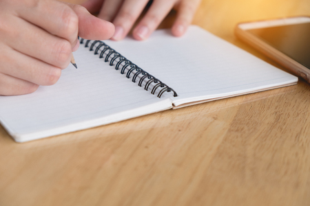 Close up. Woman hand is writting on notepad with pencil. Working business conceptの写真素材