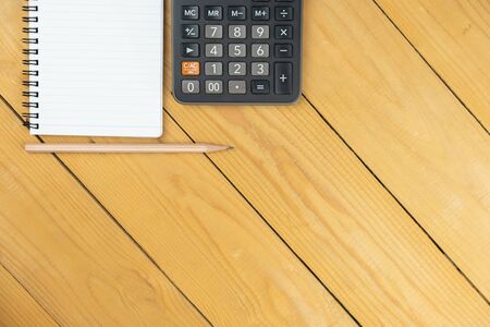 Empty notepad and calculator and pencil on wooden desk, copy space, top view background, template and presentationの写真素材