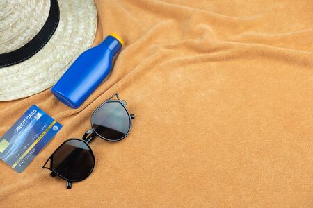 Top view of beach background. eyeglasses and credit card and sunscreen lotion and woven hats, trevel summer conceptの写真素材