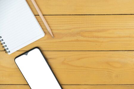 Smart phone and empty notepad and pencil on desk, mock up on screen, copy spaceの写真素材