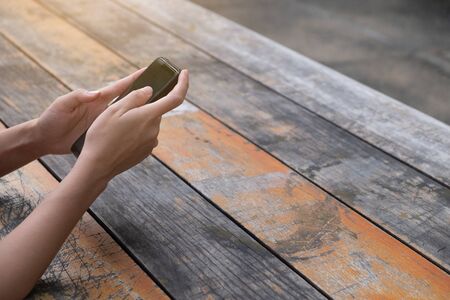 Woman using mobile phone on wooden table, copy space for use advertising and presentation, template websiteの写真素材