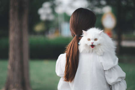Asian woman holding a white cat in a park. wearing anti virus masks during coronavirus outbreak.の写真素材
