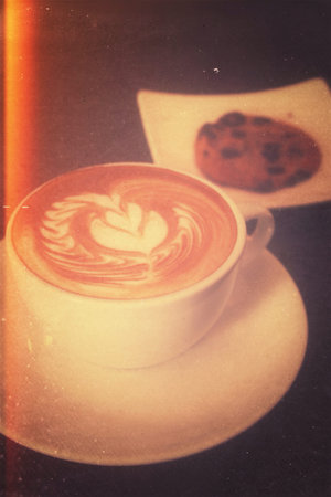 Latte or cappuccino coffee in grunge old style photograph with lighting effect