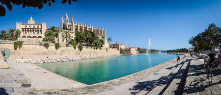 The symbol of Mallorca - The Cathedral of Palma de Mallorca. In front of it is a large pond with a fountain.の写真素材