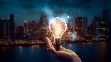 Close up of human hand holding light bulb on dark background. Mixed mediaの素材