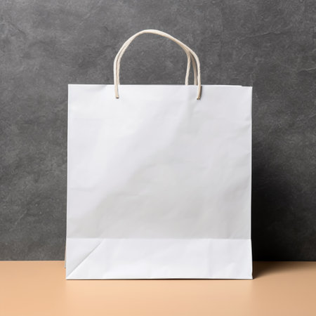 Blank white paper shopping bag on table with gray wall background.の素材