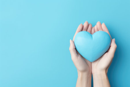Blue heart in female hands on blue background. Copy space for text.の素材